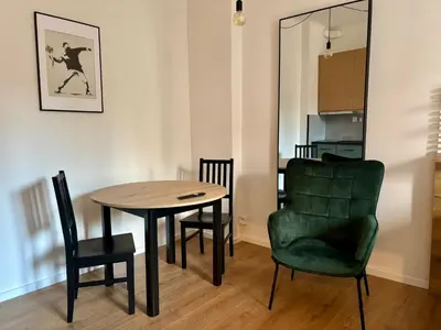 a dining room with a table and a green chair at Urban Studio - Tram Stop at Your Door, Metro 5-min Walk in Prague