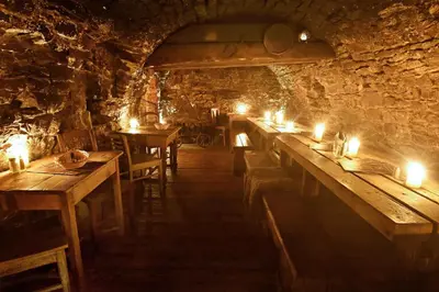 a row of tables in a cave with candles on them at Apartments U Krále Brabantského in Prague