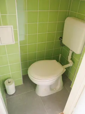 a bathroom with a toilet in a green tiled wall at Stylish studio near Jezerka park in Prague