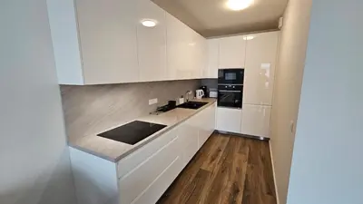 a kitchen with white cabinets and a wooden floor at Klamovka stylish Apartment by Rentez in Prague