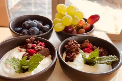 four bowls of yogurt with berries and nuts and fruits at Glamping nad Meandry v jurtě in Chyňava