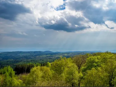 a view of a forest of trees under a cloudy sky at Glamping nad Meandry v jurtě in Chyňava