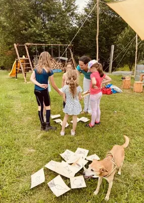 a group of people standing in the grass with a dog at Glamping nad Meandry v jurtě in Chyňava