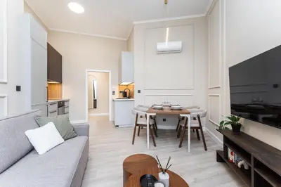 a kitchen and living room with white cabinets and a plant at Rentero Modern Spacious Apartment in Central Prague in Prague