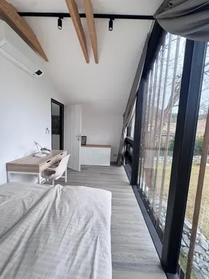 a bedroom with a bed and a desk and large windows at Green Resort Slapy