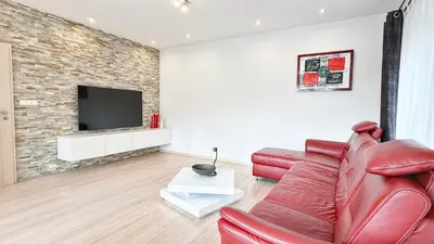 a living room with a red leather couch and a flat screen tv at Modern house with pool, 20 minutes from the center of Prague in Prague