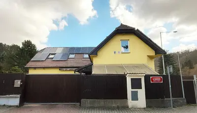 a house with solar panels on top of a fence at Modern house with pool, 20 minutes from the center of Prague in Prague