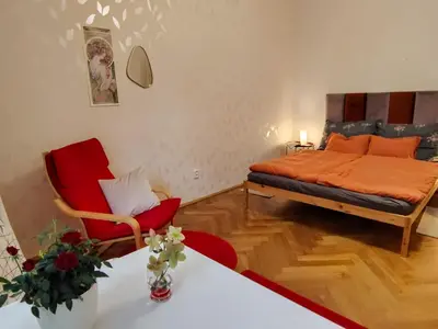 a bedroom with a bed and a red chair at Garden Apartment in Prague