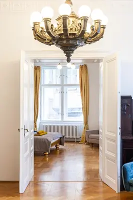 a large chandelier in a living room with a window at Royal Apartment by Charles Bridge view of Saint Nicholas Church in Prague