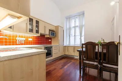 a kitchen with wooden cabinets and a table and chairs at Royal Apartment by Charles Bridge view of Saint Nicholas Church in Prague
