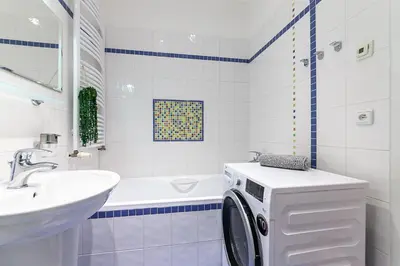 a white bathroom with a washing machine in it at Royal Apartment by Charles Bridge view of Saint Nicholas Church in Prague