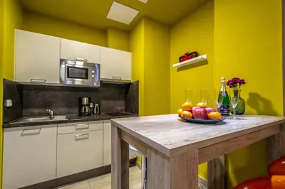 a kitchen with yellow walls and a table with fruit on it at City Center Apartments near Synagogue in Prague