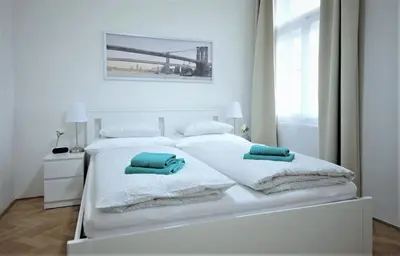 a white bedroom with two white beds and towels at Angel City Aparthotel in Prague