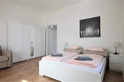 a white bedroom with a bed with pink pillows on it at Angel City Aparthotel in Prague