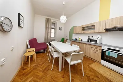 a kitchen with a table and chairs and a clock at Apartments At I.P.Pavlova in Prague