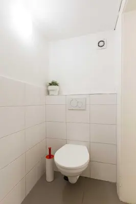 a white bathroom with a toilet and a plant at Apartments At I.P.Pavlova in Prague