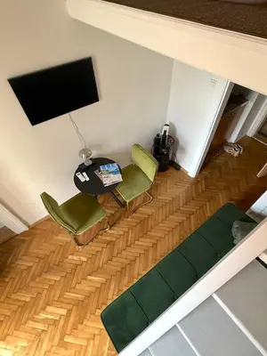 a living room with two green chairs and a television at Apartment Siroka 14 in Prague