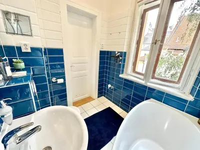 a blue tiled bathroom with a white toilet and a sink at Apartment Siroka 14 in Prague