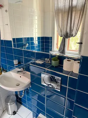 a blue tiled bathroom with a sink and a mirror at Apartment Siroka 14 in Prague