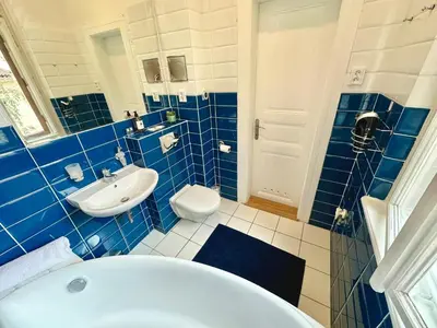 a blue tiled bathroom with a tub and a sink at Apartment Siroka 14 in Prague