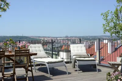 a patio with white chairs and a table on a roof at Luxury Penthouse Apartment in Prague