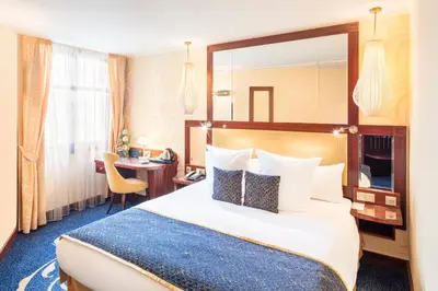 a hotel room with a large bed and a desk at Occidental Praha Wilson in Prague