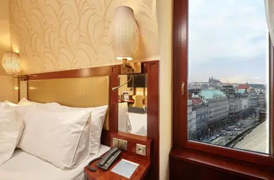 a bedroom with a bed with a window and a phone at Occidental Praha Wilson in Prague