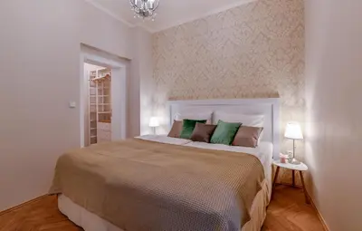 a white bedroom with a large bed with green pillows at Apartments Rybná in Prague
