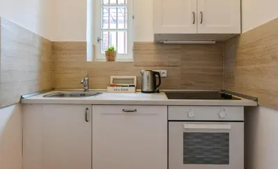 a kitchen with white cabinets and a sink at Apartments Rybná in Prague
