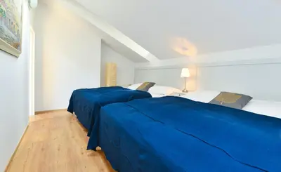 two beds in a white room with blue sheets at Apartments Rybná in Prague
