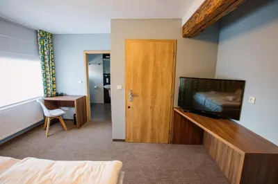 a room with a bed and a television and a door at Hotel Na Šustně in Krupá