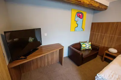 a room with a flat screen tv and a chair at Hotel Na Šustně in Krupá