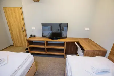 a room with a tv on a desk with two beds at Hotel Na Šustně in Krupá