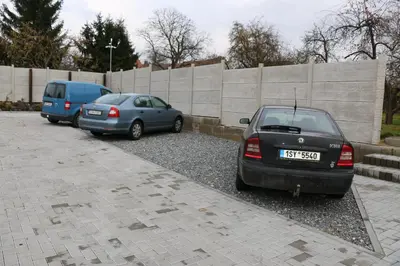two cars parked in a parking lot next to a fence at Penzion Kotvas in Milovice