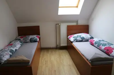 two beds in a small room with a window at Penzion Kotvas in Milovice