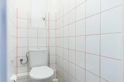 a white tiled bathroom with a toilet and a mirror at Apartment Na Kozacce 6 in Prague