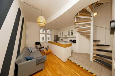 a living room with a couch and a spiral staircase at Apartment Na Kozacce 6 in Prague