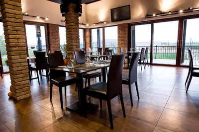a dining room with tables and chairs and windows at Rooms & Restaurace Na Jitrách in Semice