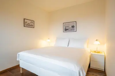 a bedroom with a white bed and two lamps at Rooms & Restaurace Na Jitrách in Semice