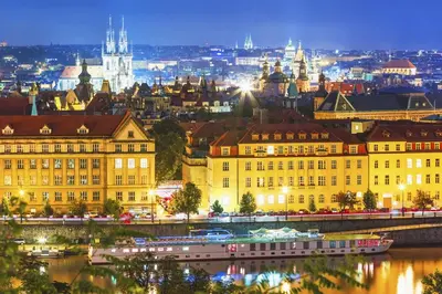 a city skyline with buildings and a river at night at Attic Apartment City Center in Prague