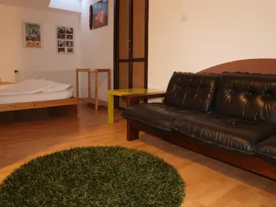 a living room with a leather couch and a rug at Attic Apartment City Center in Prague