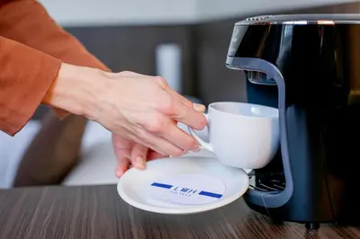 a person holding a coffee cup next to a toaster at Apartments Embassy by LH in Prague