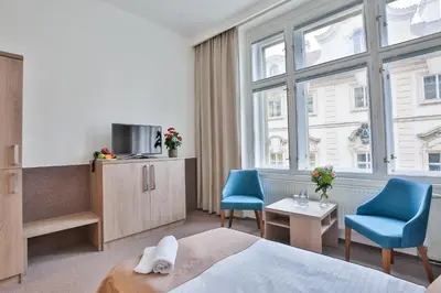 a hotel room with a bed and two blue chairs at Apartments Embassy by LH in Prague