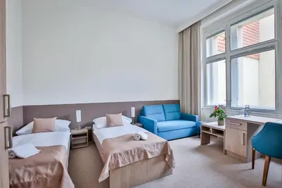 a hotel room with two beds and a blue chair at Apartments Embassy by LH in Prague