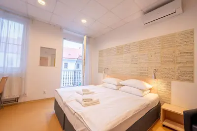 a bedroom with a large bed with white sheets and pillows at Drunken Monkey Hostel in Prague