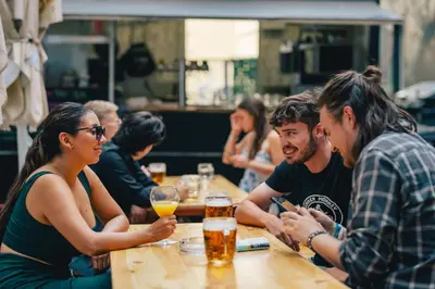 a group of people sitting at a table with drinks at Drunken Monkey Hostel in Prague