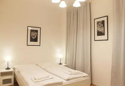 a white bedroom with a bed and two lamps at Modern apartment Michalska 6 in Prague