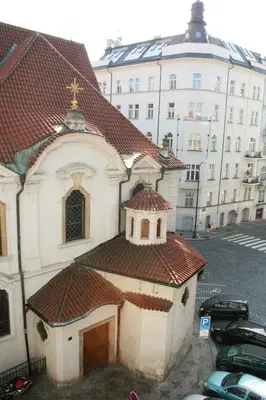 a small white church with a red roof in front of a building at Apartment Lea in Prague