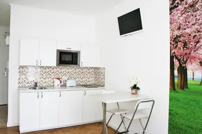 a kitchen with white cabinets and a table with chairs at Apartment Lea in Prague