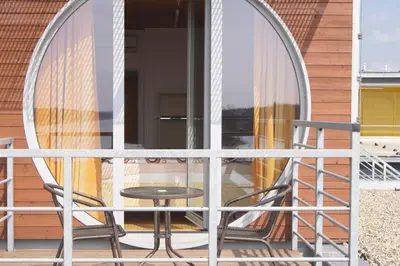 a table and chairs on a balcony with a round mirror at Labe Aréna Račice in Štětí